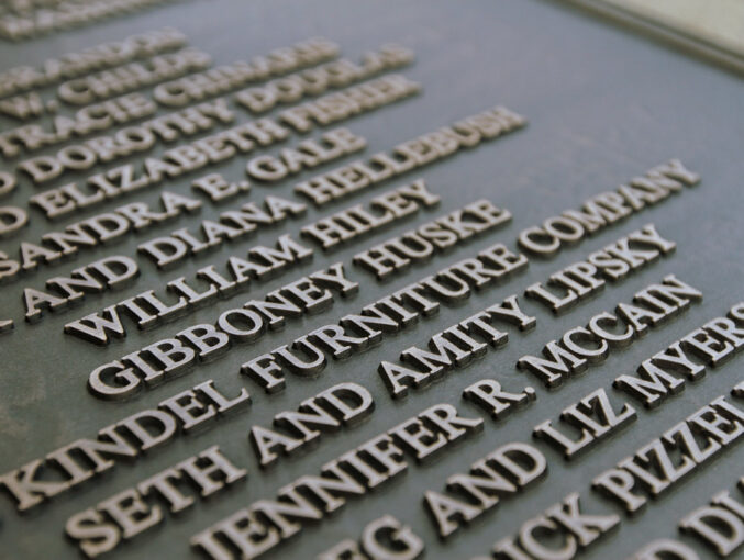 14"w x 18"h Cast bronze plaque Oxidized Chem40 Finish raised lettering and border add Custom extra deep cast border with arc top and bottom add R5 Rosettes with screws through face Background travertine with standard dark finish per process MATTE Cle