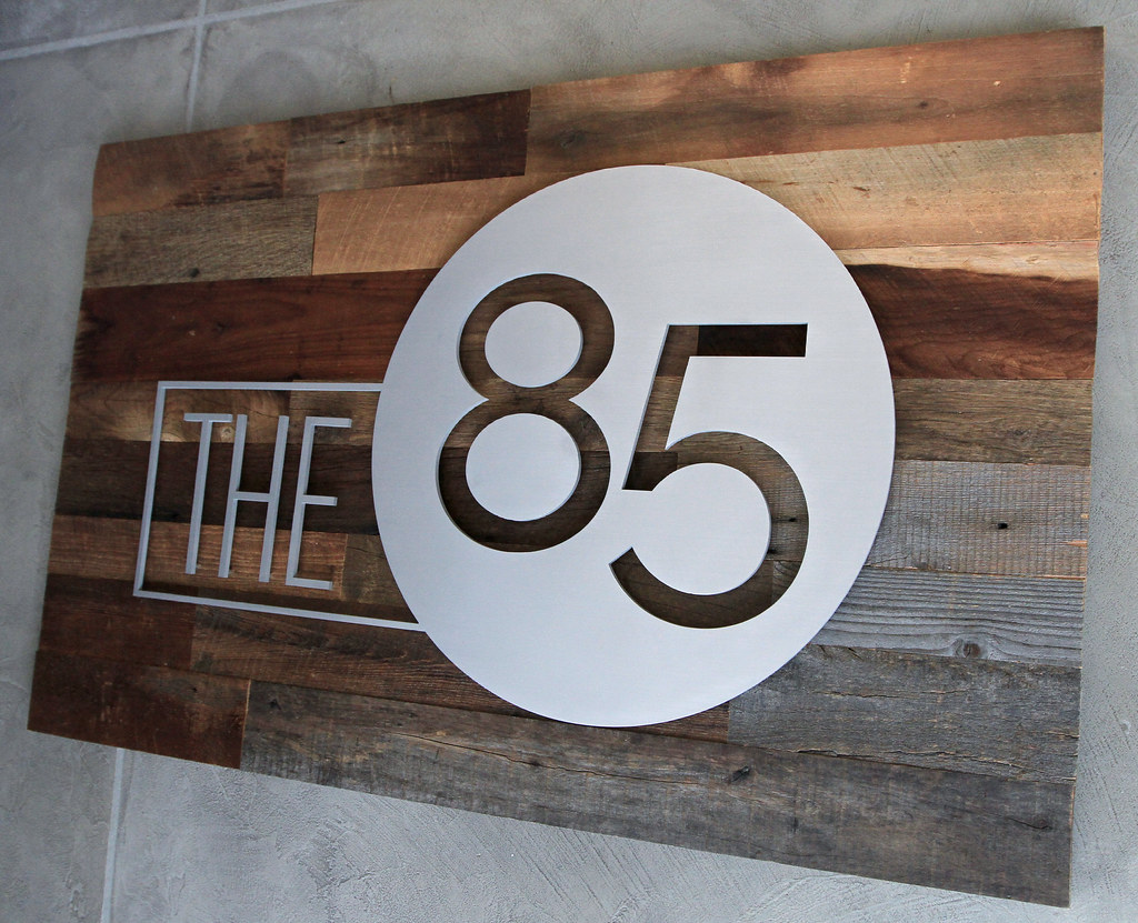 48" x 36" reclaimed wood panel with brushed aluminum logo assembled with spacers on face Installed with a cleat on the back of the panel to be flush to wall