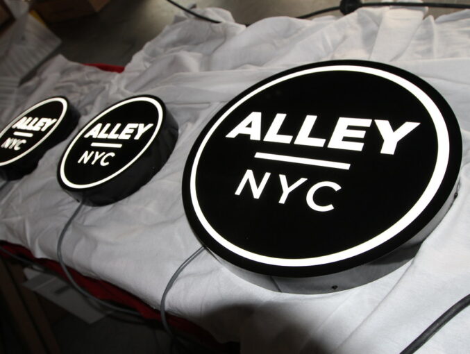 Fabricated circle panel signs with reverse cut logo graphics for lighting interior or exterior use