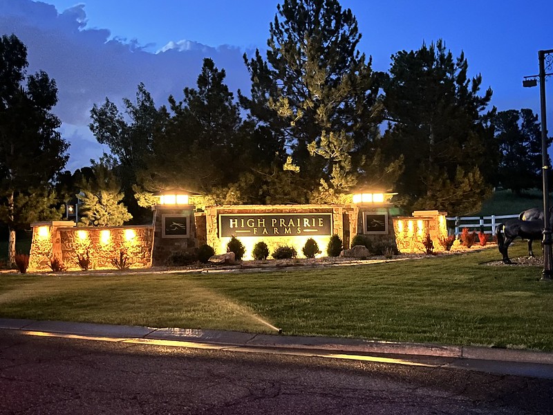 Monument sign illuminated using exterior lighting that is part of the landscape.